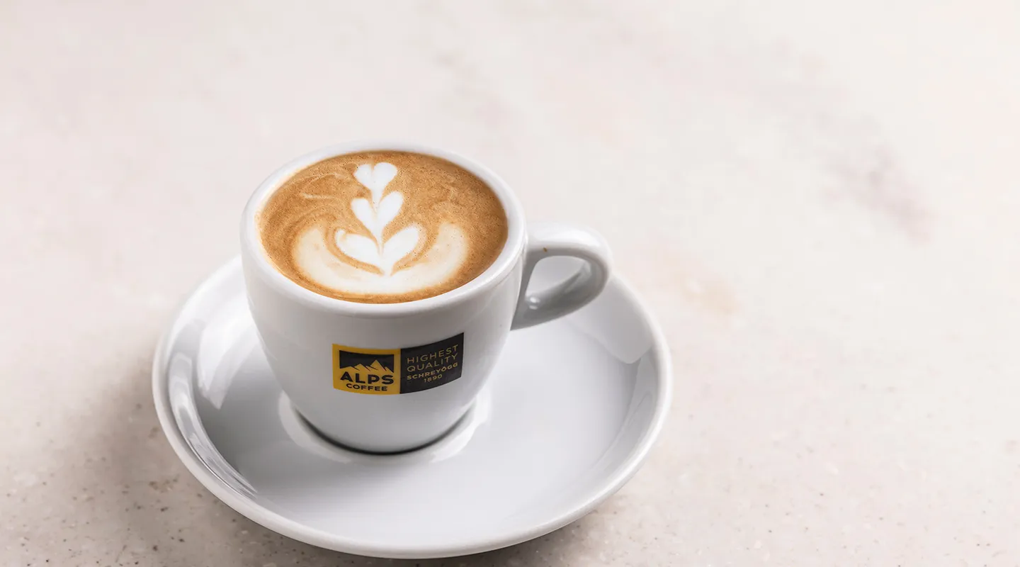 Alps Coffee cappuccino with latte art floral pattern in white cup on Alps Coffee saucer