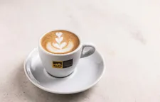 Alps Coffee cappuccino with latte art floral pattern in white cup on Alps Coffee saucer