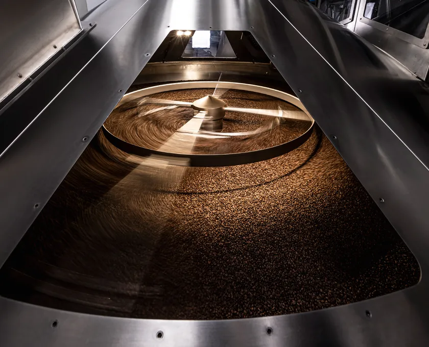 Kaffeebohnen kühlen nach dem Rösten auf rotierendem Edelstahl-Kühltablett in der Röstanlage
